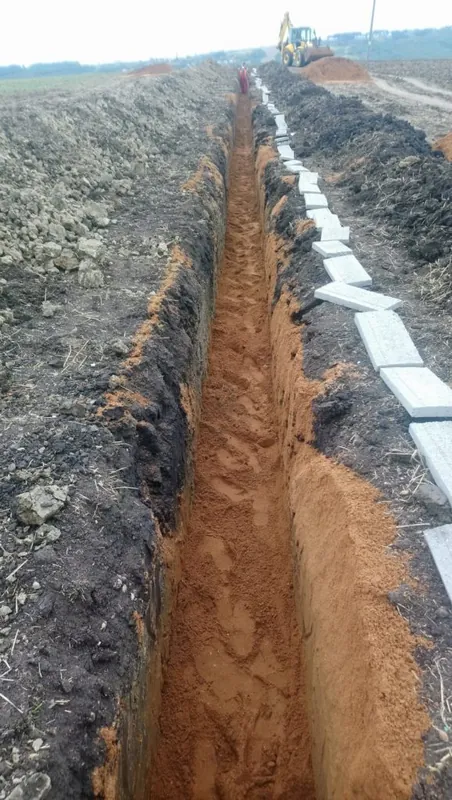 Prázdná rýha v poli, podél ní bílé betonové desky